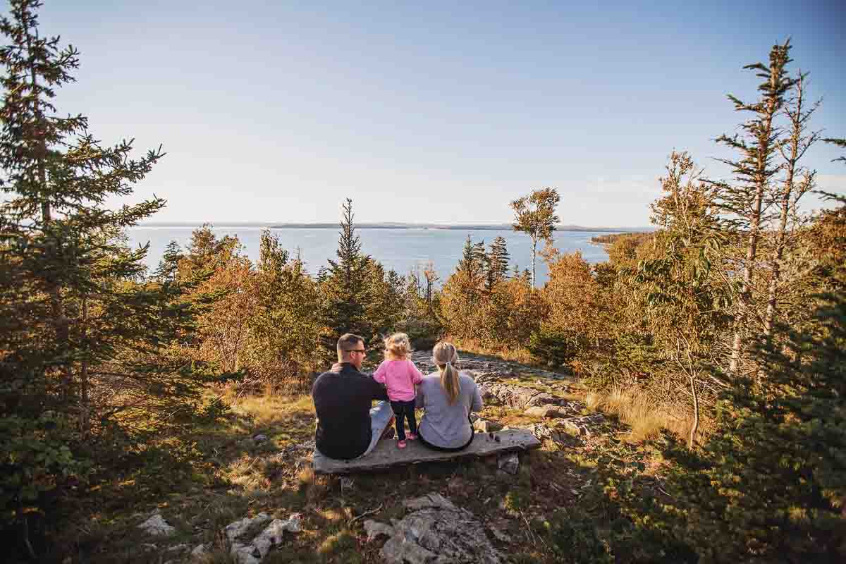 family sitting on a bench in one of Maine Coast Heritage Trust's preserves