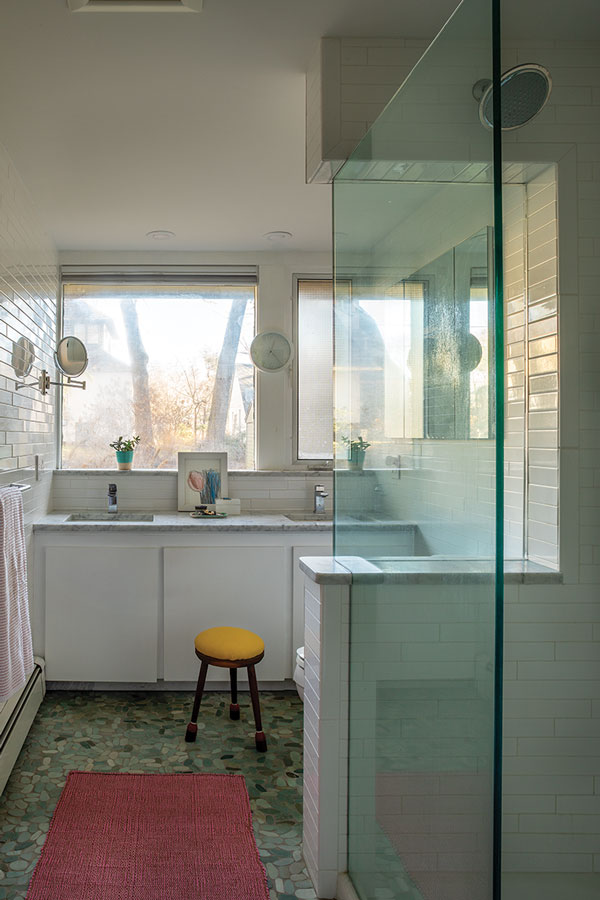 bathroom with floor-to-ceiling subway tile, a marble countertop, and seaglass-like pebble floor