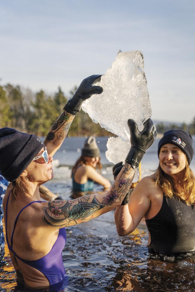 Cold Tits, Warm Hearts swim group members in the water holding up a chunk of ice