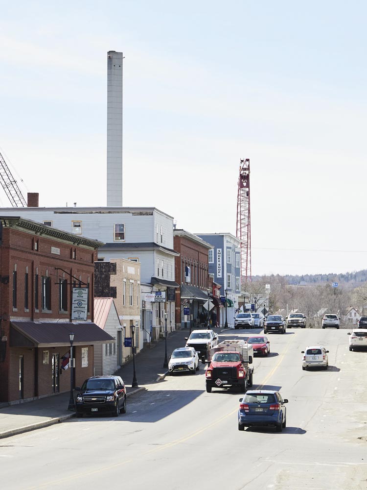 the mill’s smokestack and cranes loom over Madison’s Main Street