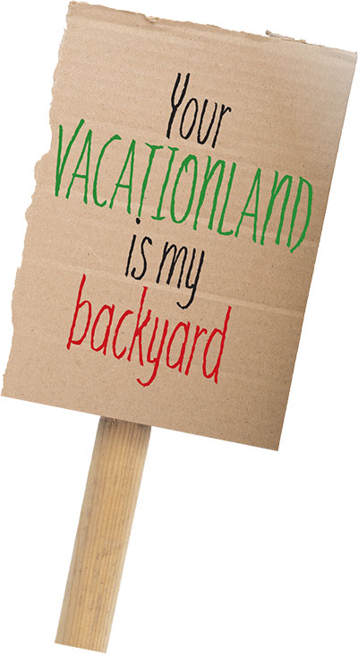 cardboard sign that reads "Your VACATIONLAND is my backyard"